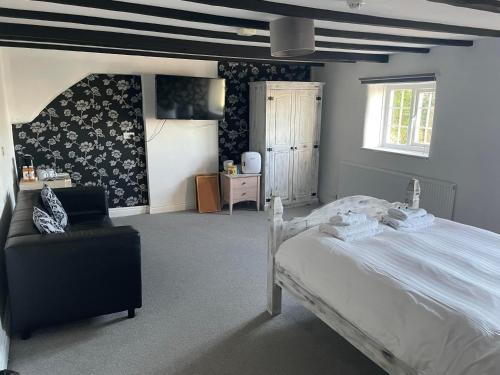 um quarto com uma cama branca e uma cadeira em The Farmers Arms Inns em Catterick Bridge