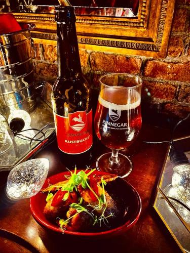 a bottle of beer and a plate of food and a glass at Malin TownHouse in Malin