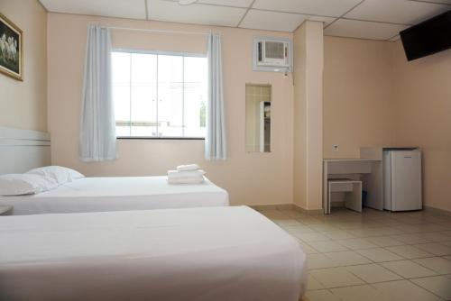 a hotel room with two beds and a window at Lord Hotel Camburi in Vitória