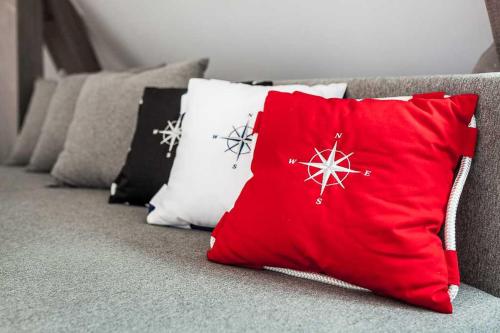 a red pillow sitting on a couch with other pillows at Sopot Pier Apartments by OneApartments in Sopot