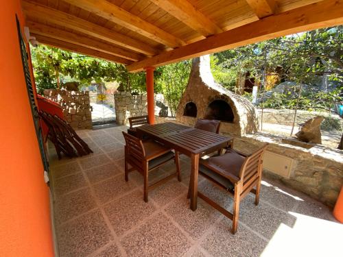 einen Holztisch und Stühle auf einer Terrasse mit Kamin in der Unterkunft Villetta Corallo IUN Q1810 in Porto Pollo