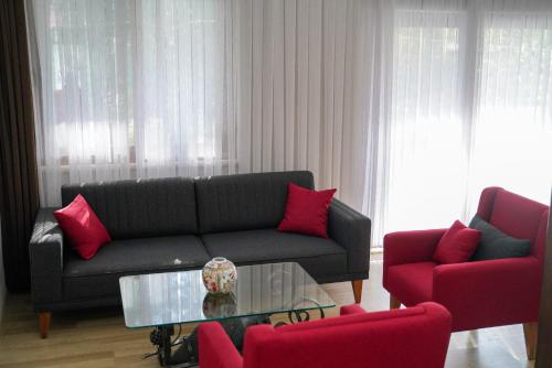 a living room with a couch and two red chairs at Keyif Pension & Aparts in Cıralı