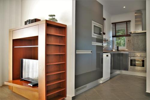 a kitchen with a tv in a wooden cabinet at Pine Tree Apartments - Praia da Coelha - Albufeira in Albufeira