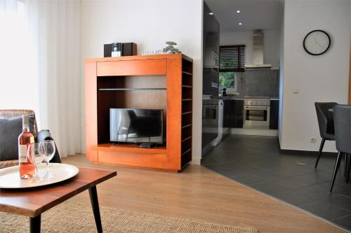 a living room with a fireplace with a table and a kitchen at Pine Tree Apartments - Praia da Coelha - Albufeira in Albufeira