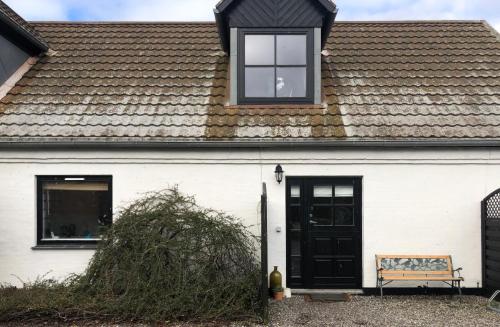 a white house with a black door and a bench at AppleFlower Farm retro apartment in Lillerød