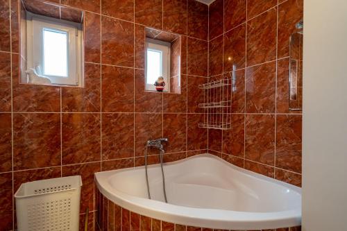 e bagno con vasca e piastrelle marroni. di Apartman JOZIC a Knin (Tenin)