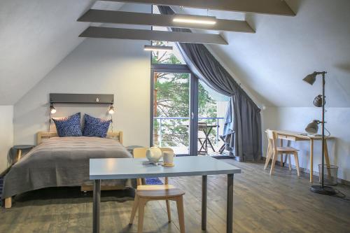 a bedroom with a bed and a table and a window at Coastal Home Piedāgi Ūši in Kolka