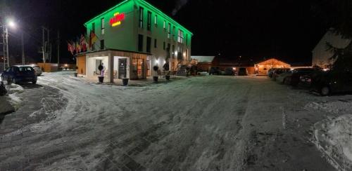 a building with a green roof on a snow covered street at ALPIN rooms in Topliţa