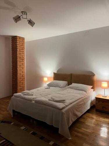 a bedroom with a large bed with two lamps at Pensiunea Poiana Luminoasă in Bughea de Jos