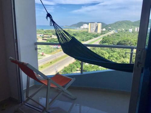 eine Hängematte und ein Stuhl auf einem Balkon mit Aussicht in der Unterkunft Pozos Colorados Santa Marta - Apartamento 1005 hermosa vista in Santa Marta