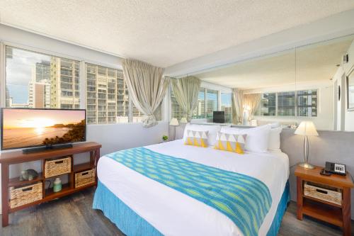 a hotel room with a large bed and a flat screen tv at Beautiful Studio in the Heart of Vibrant Waikiki in Honolulu