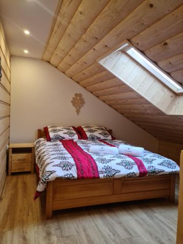 a bedroom with a bed in a attic with a window at Apartamenty Pod Skałką in Szaflary