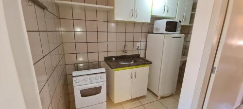 a small kitchen with a stove and a refrigerator at diRoma Fiori - Apartamentos JN in Caldas Novas