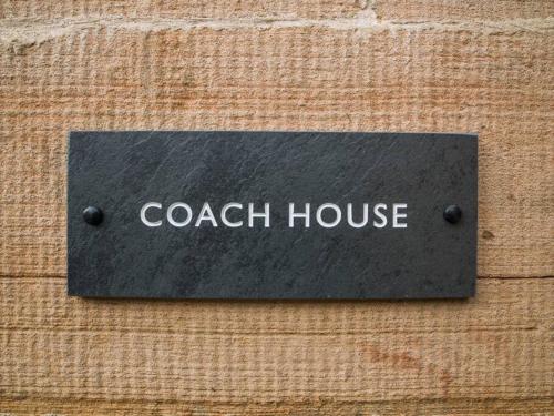 a black sign that says coach house on a wooden wall at Stunning Edinburgh 1820s stables converted studio in Edinburgh
