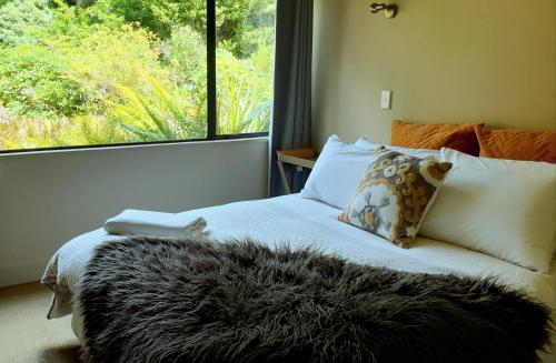a bedroom with a bed with a large window at Beech Tree Lodge in Ohakune