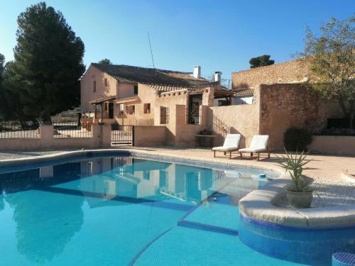 una piscina con 2 sillas y una casa en Finca Guillermo Murcia, en Cañada del Trigo