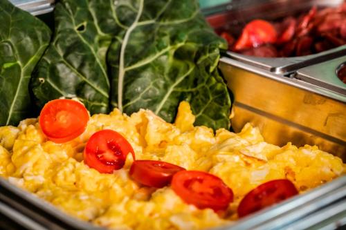 a tray of scrambled eggs with tomatoes and spinach at O Costão do Sol in Balneário Camboriú