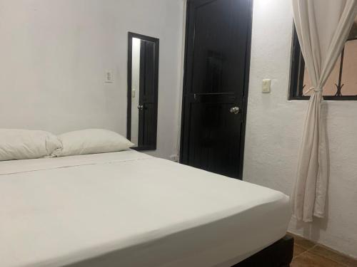 a white bed in a room with a black door at Moonshine Hotel in Playa del Carmen