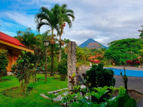 un complejo con piscina y montaña de fondo en Hotel Arenal Country Inn, en Fortuna