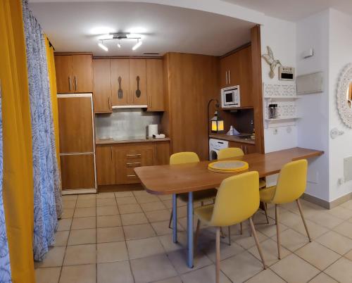 cocina y comedor con mesa de madera y sillas amarillas en Residencial Esquinzo 2, en Playa de Jandía