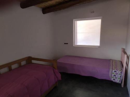 two beds in a room with a window at Piedra Campana alojamiento in Tilcara