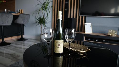 a bottle of wine and two wine glasses on a table at Przystań Apartament Aqua in Reda