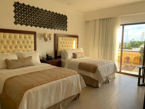 a hotel room with two beds and a balcony at Real Hispano in Valladolid
