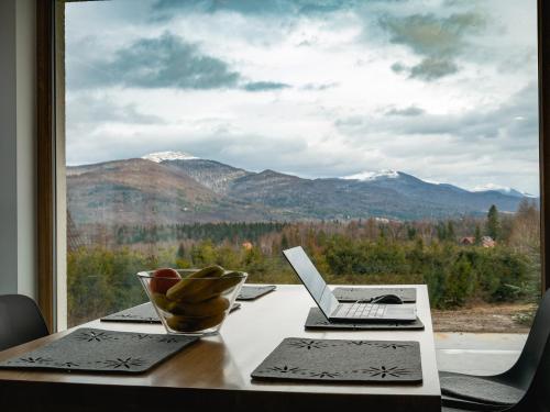 a table with a laptop on it with a view of mountains at Białe Chyże in Wetlina