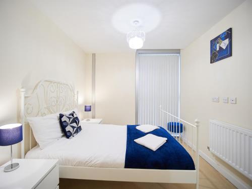 a white bedroom with a bed with a blue blanket at Cosy One Bed City Apartment -The Hub in Milton Keynes