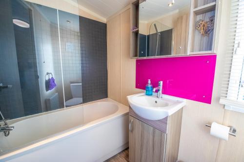 a bathroom with a sink and a bath tub and a sink at Sea 'n' Stars Platinum Plus Holiday home with Views, Free Wifi and Netflix in Camber