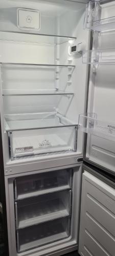 un réfrigérateur vide avec sa porte ouverte dans une cuisine dans l'établissement Appartement 65m² Paris - DisneyLand - RER A, à Noisy-le-Grand