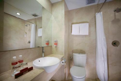 a bathroom with a toilet and a sink and a shower at favehotel Hyper Square in Bandung