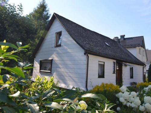 una pequeña casa blanca con techo negro en Holiday home in Ramsbeck with garden, en Bestwig