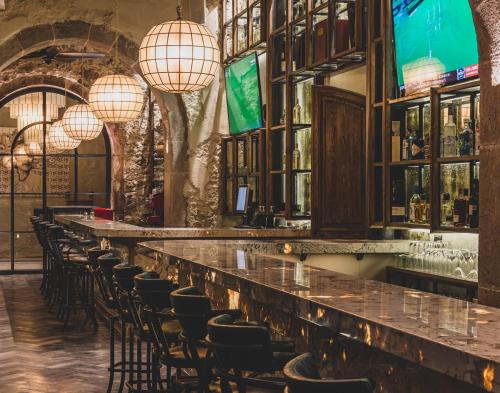 a row of bar seats in a bar with chandeliers at Casa 1810 Parque Hotel Boutique in San Miguel de Allende