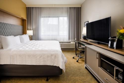 a hotel room with a bed and a flat screen tv at Holiday Inn - Long Island - ISLIP Arpt East by IHG in Holtsville
