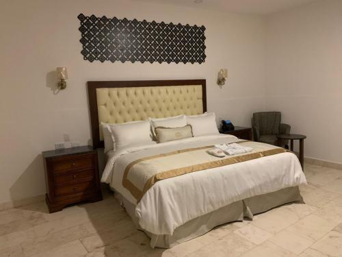 a bedroom with a large bed and a chair at Real Hispano in Valladolid