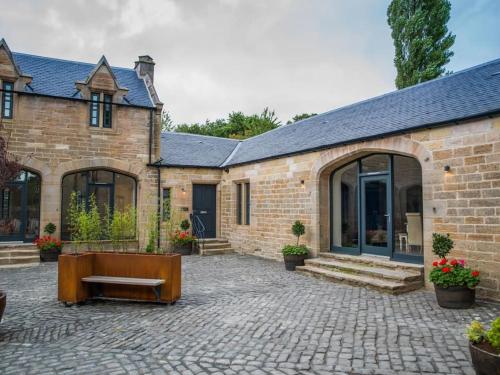 a brick house with a bench in front of it at Stunning Edinburgh 1820s stables converted house in Ratho