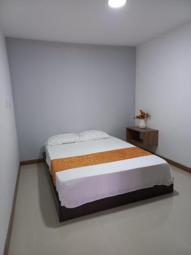 a white bedroom with a bed and a table at Apartamento FL Martinz 2 in Manizales