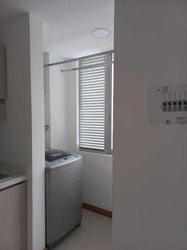 a white kitchen with a washer and a window at Apartamento FL Martinz 2 in Manizales