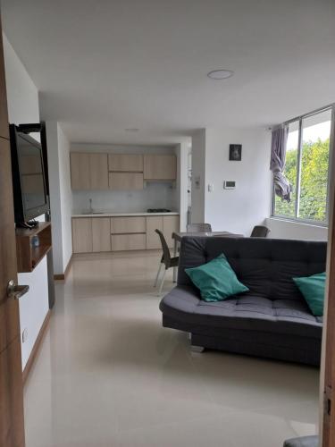 a living room with a couch and a kitchen at Apartamento FL Martinz 2 in Manizales