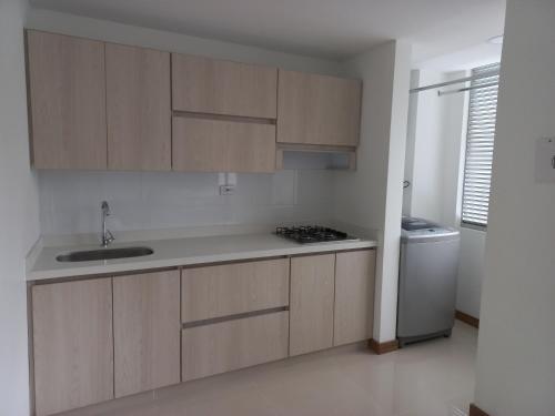 a kitchen with wooden cabinets and a sink and a stove at Apartamento FL Martinz 2 in Manizales