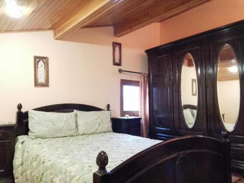 1 dormitorio con cama grande de madera y espejo en appartement chalet, en Imouzzer Kandar
