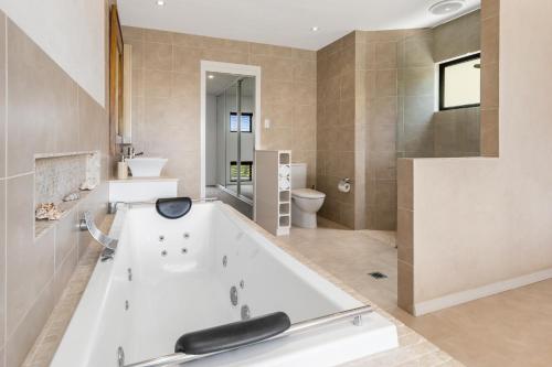 ein großes Bad mit einer Badewanne und einem WC in der Unterkunft Villa Baci Nobby Beach in Gold Coast