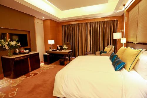 a hotel room with a large bed and a desk at JinJiang International Hotel Urumqi in Ürümqi