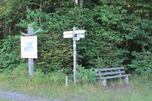 a wooden sign next to a bench next to a bush at Apartments bei Familie Liebl in Sankt Oswald