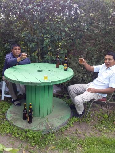dos hombres sentados alrededor de una mesa verde con botellas de cerveza en Hospedaje el Motilon, en Quito