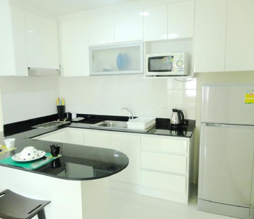 a white kitchen with a sink and a refrigerator at Charming Resident near BTS Ekkamai Station in Bangkok
