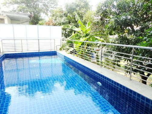a blue swimming pool with a fence and trees at Charming Resident near BTS Ekkamai Station in Bangkok