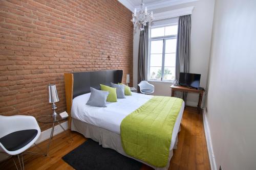 a bedroom with a large bed with a brick wall at New Voga Guesthouse in Valparaíso