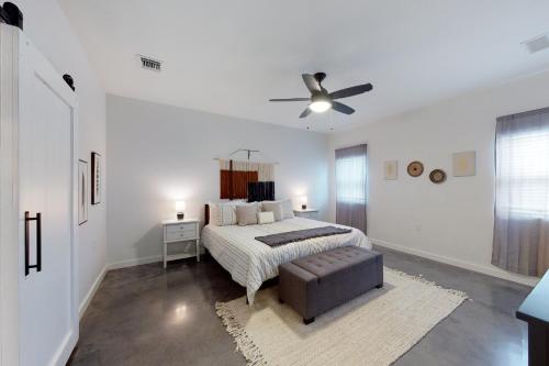 a white bedroom with a bed and a ceiling fan at Dry Creekside Casita in Fischer